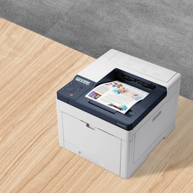 A laser printer on a wooden desk with a printed color page