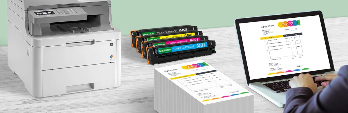 A laser printer, four GREENBOX toner cartridges, a stack of printed pages and a laptop on a desk